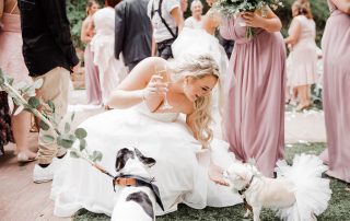 A woman in a wedding dress feeding a dog.
